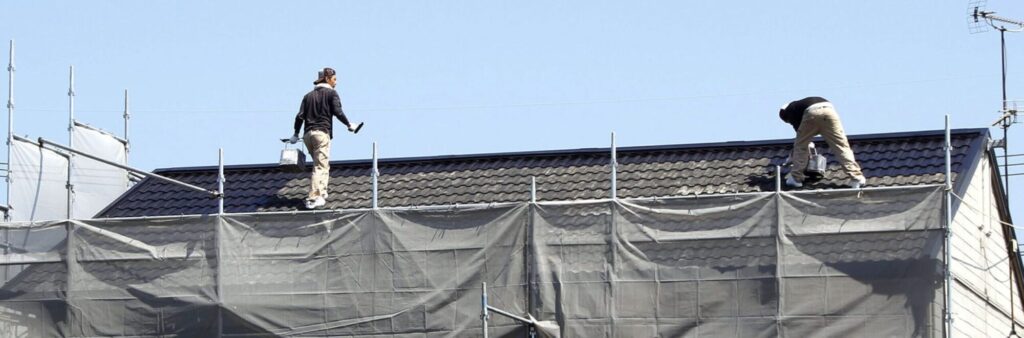 屋根の上で作業をする株式会社匠美のスタッフ